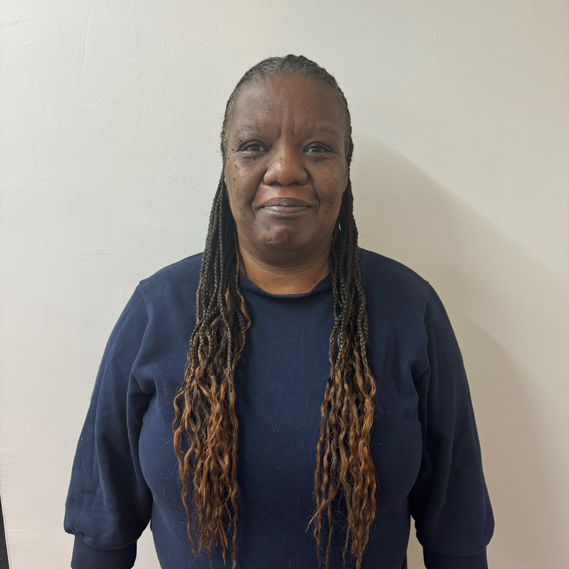 A woman with long braids standing in front of a white wall